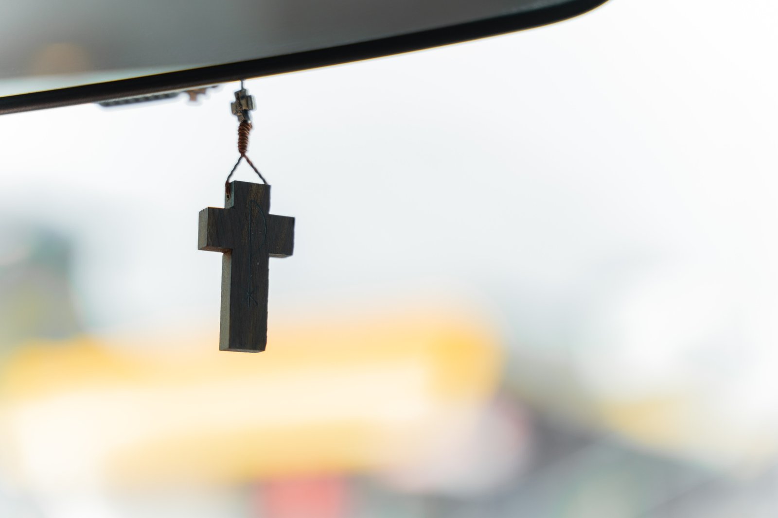 Christian crucifix hanging on car rear mirror. Concept of religiosity and faith in god